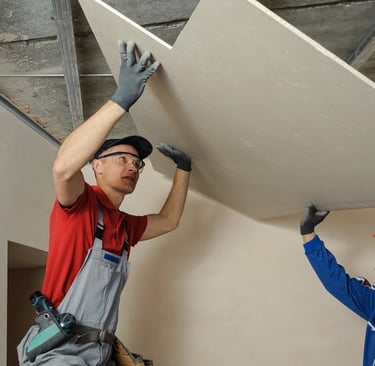 worker adding fresh drywall to a ceiling repair