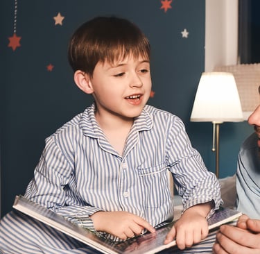 a father and two children are laying on a bed reading a book