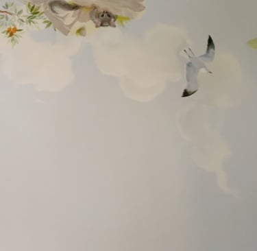 Hand-painted possum peeking from tree branches with clouds and flying gull — detail from Australian nursery mural