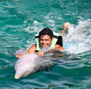 a man in a life jacket is smiling and holding a dolphin dolphines punta cana