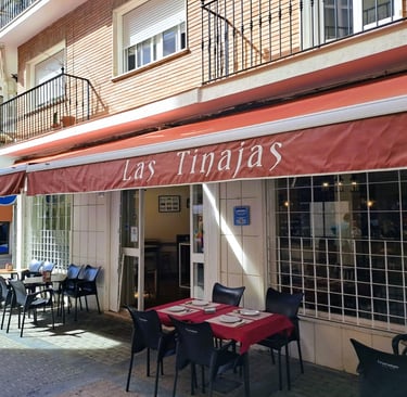 Historia del Bar Las Tinajas Huelva reflejada en su fachada exterior y terraza, con mesas listas para recibir a los clientes.