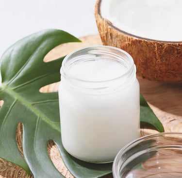 Fotografia de un recipiente de aceite cristalizado de coco junto a unos cocos