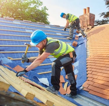 2 roofing workers installing orange tiles