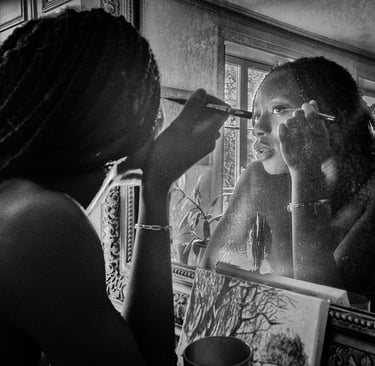 Photo artistique noire et blanc d'une jeune femme noire qui se requi se remaquille dans le miroir d'un intérieur haussmannien