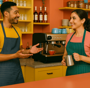 Baristas smiling and talking while preparing drinks behind a colorful, modern café counter.