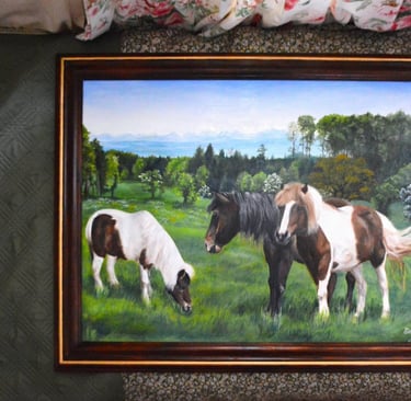 a framed painting of three horses grazing in a field