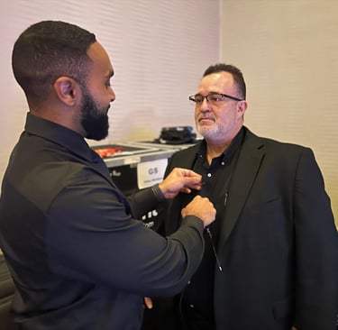 a man in a suit and glasses is getting mic'd up