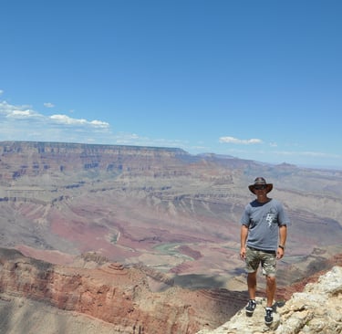 a man standing on a cliff overlooking a vast view of the grand canyon