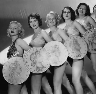 Low‑angle shot of Gold Diggers of 1933 chorus girls holding giant coins in “We’re in the Money.”