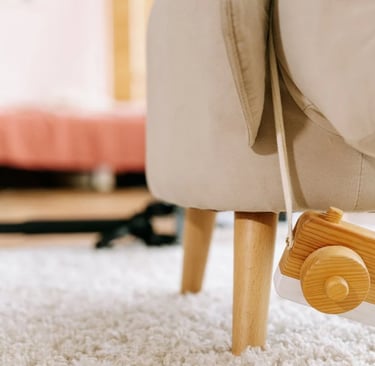 Câmera de brinquedo pendurada em cadeira infantil estofada sobre tapete claro.