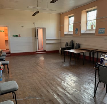 Former school hall with worn wooden floors and original windows before renovation