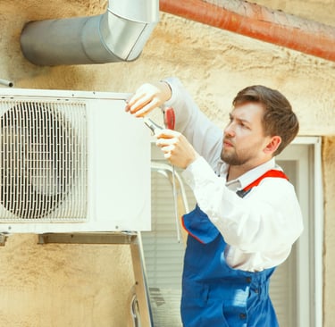 a man in overalls and overalls is fixing a heat pump