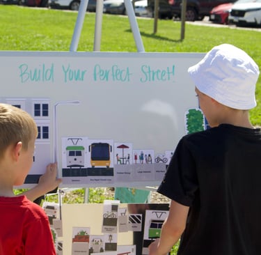 Two children at a whiteboard activity titled "Build Your Perfect Street!"