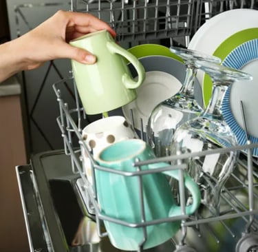 Plates, cups and glasses inside a dishwasher basket