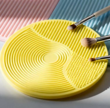 A round, yellow silicone mat with ripple textures, used for cleaning makeup brushes.