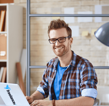 a man sitting at a desk with a laptop computer freelancing