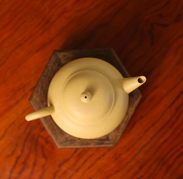 An overhead view of a yellow teapot placed on a wooden stand