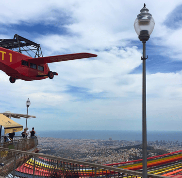 a red plane flying over Barcelona city in Tibidabo amusement park