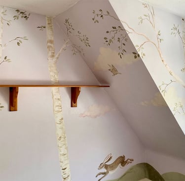 Wide angle on a wrap-around kid’s mural with a painted birch grove and a hare jumping on green ground.