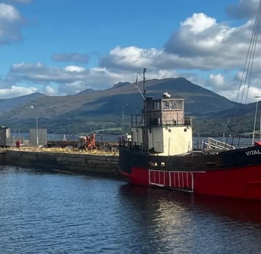 a boat docked at a pier with hills in the background