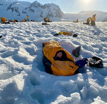a person laying on the snow in a warm sleeping bag