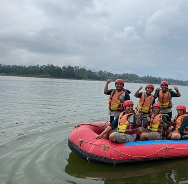 Delapan orang bersemangat di perahu karet merah melakukan rafting di Situ Cileunca Bandung, mengenakan jaket pelampung oranye