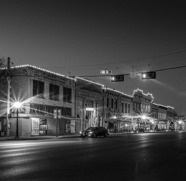 Night photo of Austin Ave in Georgetown, Texas, with it's historic buildings illuminated by streetlights 