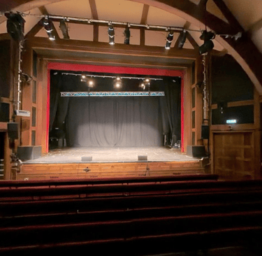 The Pleasance Theatre, a theatre with a large stage and cushioned benches.