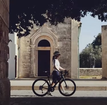 a woman riding a bicycle through a narrow alley