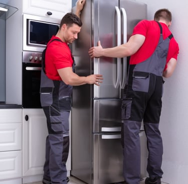 two men in red shirts and overalls standing in front of a refrigerator