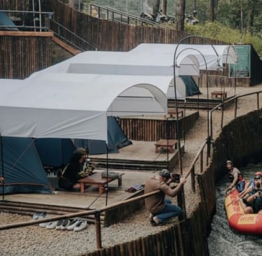 Rombongan rafting di sungai Pangalengan dekat tenda camping riverside, menyorot petualangan dan penginapan alam.