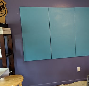 Four stretched canvas panels painted a seashore blue.