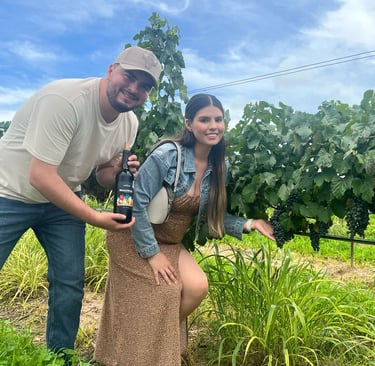 Pareja en un viñedo tomando fotos con las uvas