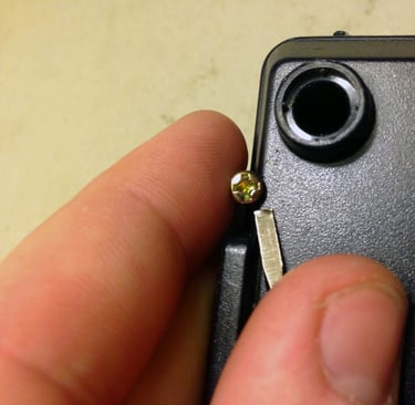 a person holding a small piece of metal with a small screwr