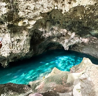 a man standing on a cliff face down into a cave santo domingo punta cana
