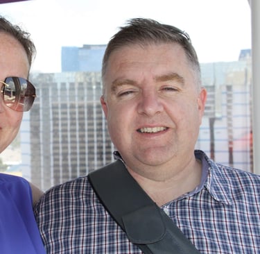 Two adults posing inside observation wheel cabin with city skyline in background, capturing a moment of leisure