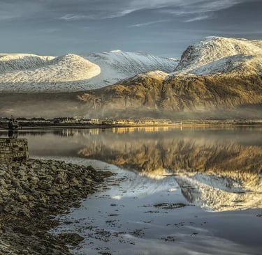 Winter view of Ben Nevis mountain range from the base with mist rising over the peaks in Scotland