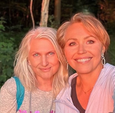 Two smiling women in nature at sunset, glowing with warmth, friendship, and joyful connection.