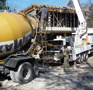 Un camión hormigonera con una grúa al fondo
