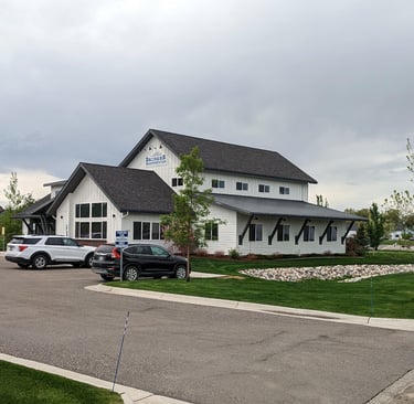 a white house with a black roof and a white car parked in front of it