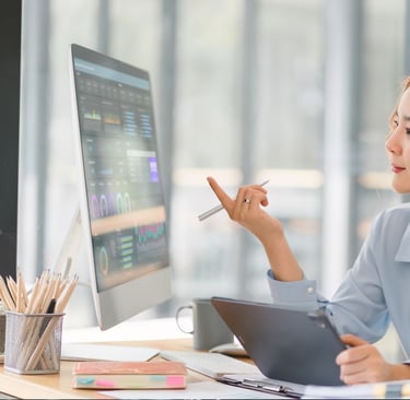 a woman sitting at a desk with a computer and a pen-ai integrated digital marketing