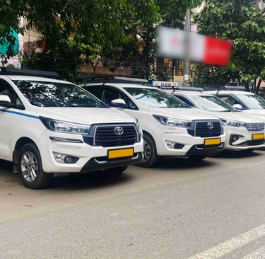 A row of white Toyota Innova Crysta taxis parked on a city street for commercial rental services.