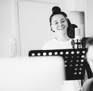 Female vocalist recording in studio booth during vocal session