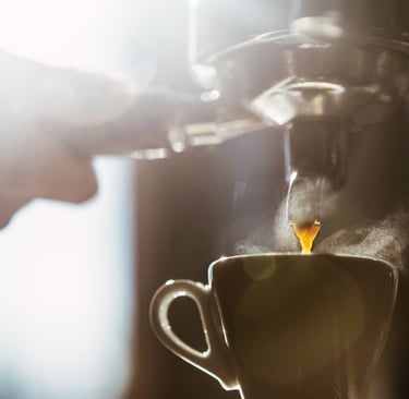 a person is pouring a cup of coffee into a cup