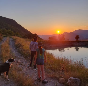people walking down a path and looking at the beatiful sunset above the mountains and a lake