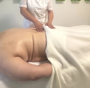 Séance de massage du dos dans une salle de soins, avec une praticienne massant une personne allongée