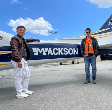 a man standing next to a plane with a man in a vest