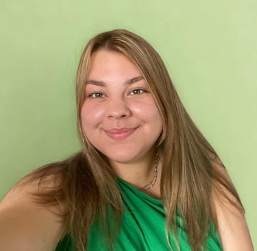 Glimlachende vrouw met lang bruin haar in groene top tegen zachte groene achtergrond.