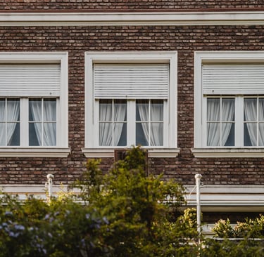 façade de maison avec trois fenêtres aux volants roulants blancs