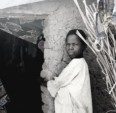 a boy in a white robe standing in front of a stone wall